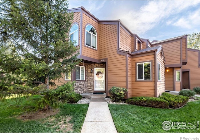 view of front of home with stone siding and a front lawn