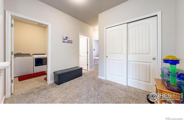 carpeted bedroom with washing machine and dryer and a closet