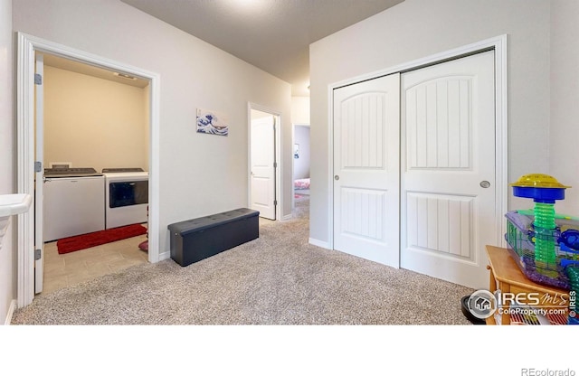 bedroom featuring separate washer and dryer, light carpet, and a closet