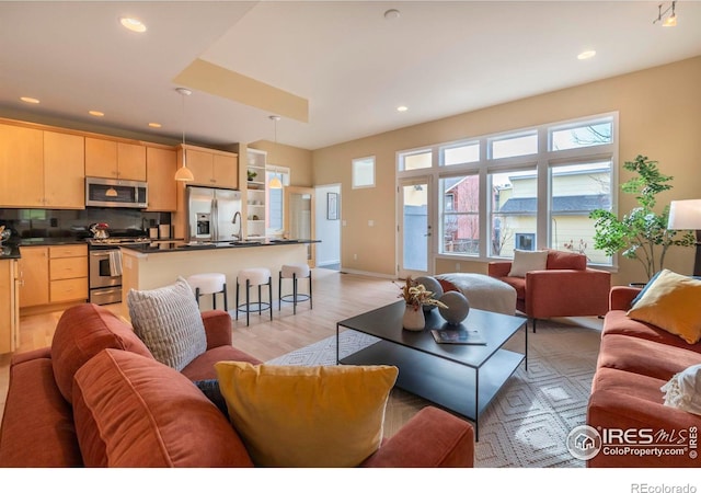 living room with sink, plenty of natural light, and light wood-type flooring