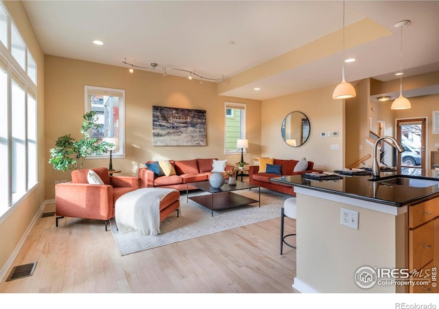 living area with light wood-type flooring, baseboards, visible vents, and recessed lighting