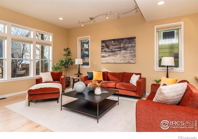 living room with track lighting, wood finished floors, a wealth of natural light, and recessed lighting