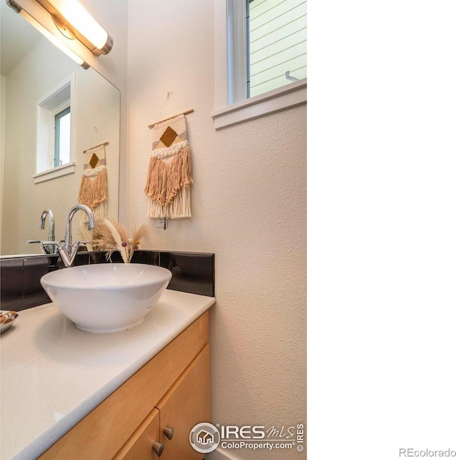 bathroom with a textured wall and vanity