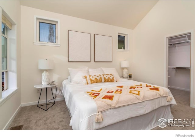 carpeted bedroom with vaulted ceiling, a spacious closet, a closet, and baseboards