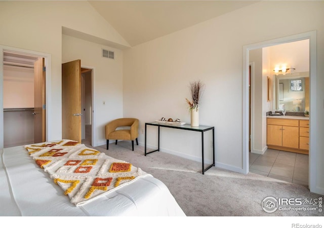 carpeted bedroom with ensuite bathroom, a closet, a walk in closet, and vaulted ceiling