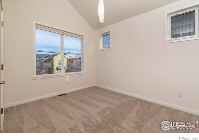 carpeted empty room featuring baseboards, visible vents, and vaulted ceiling