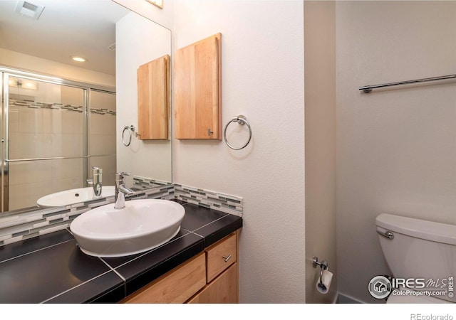 full bathroom featuring toilet, recessed lighting, vanity, visible vents, and tiled shower