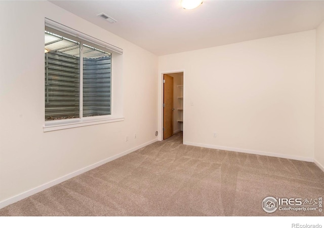 unfurnished room featuring carpet, visible vents, and baseboards