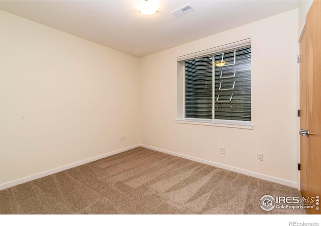 unfurnished room with carpet, visible vents, and baseboards