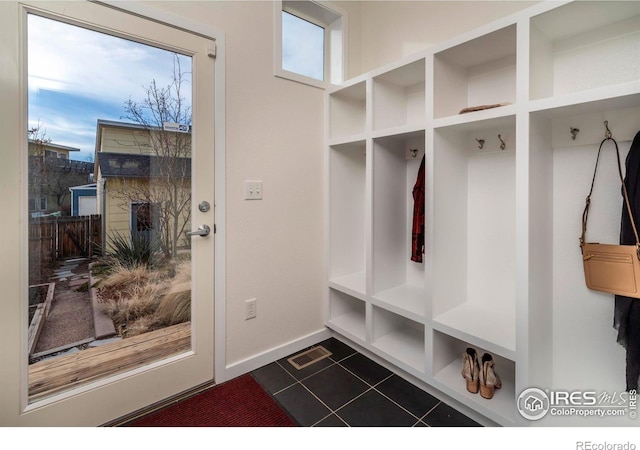 mudroom with visible vents, dark tile patterned floors, and baseboards