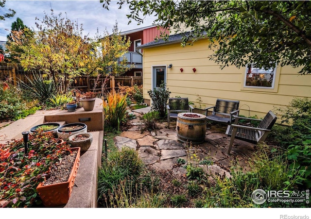 view of patio with an outdoor fire pit, fence, and a garden