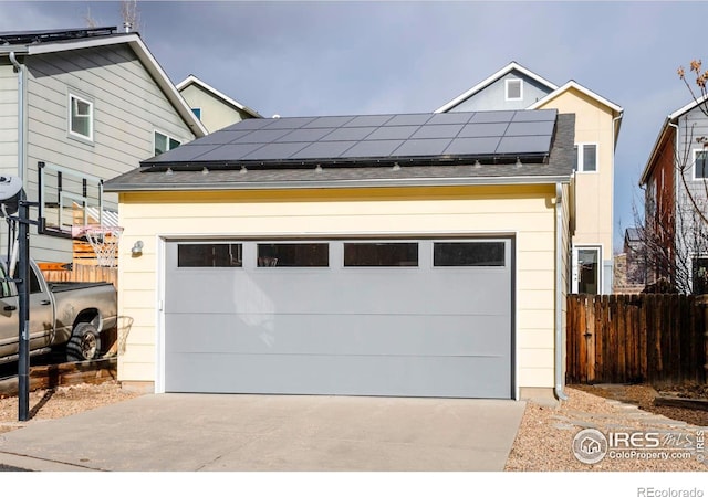 detached garage featuring fence and solar panels