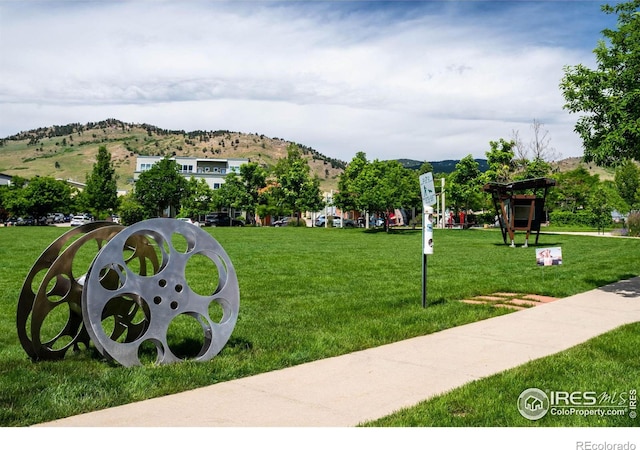 view of property's community featuring a lawn and a mountain view