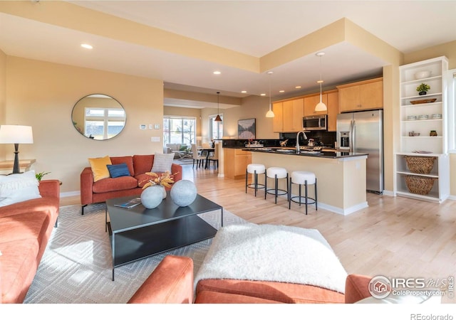 living room featuring light wood-type flooring, baseboards, and recessed lighting