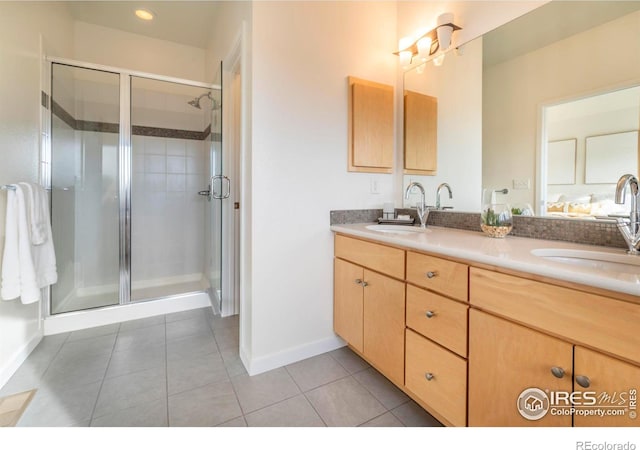 bathroom featuring double vanity, a shower stall, a sink, and tile patterned floors