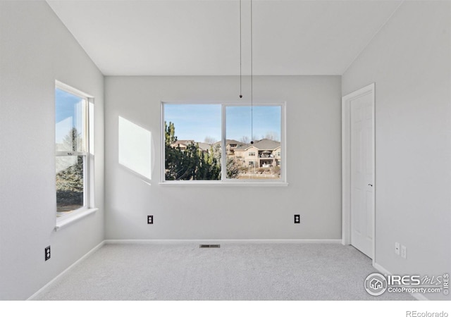 unfurnished room featuring plenty of natural light, lofted ceiling, and light carpet