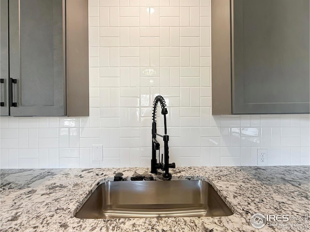 interior details with backsplash, light stone counters, and sink