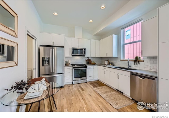 1998 Foxtail Ln Unit B, Lafayette, CO 80026 - kitchen featuring stainless steel appliances, a sink, white cabinets, light wood-type flooring, and decorative backsplash