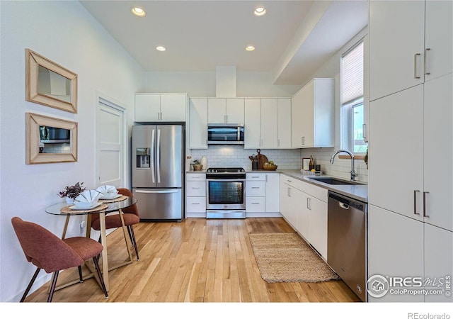 1998 Foxtail Ln Unit B, Lafayette, CO 80026 - kitchen with appliances with stainless steel finishes, a sink, light wood-style floors, backsplash, and white cabinetry