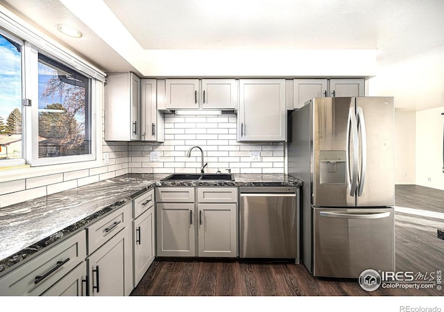 kitchen with appliances with stainless steel finishes, dark stone countertops, gray cabinetry, and sink