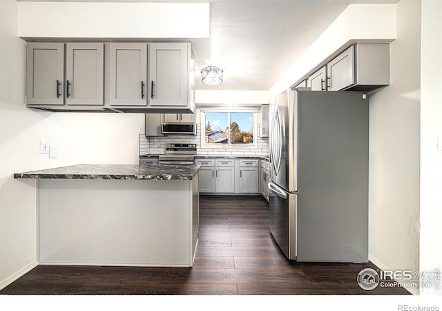 kitchen with appliances with stainless steel finishes, dark stone countertops, and gray cabinets