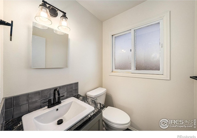 bathroom featuring toilet, vanity, and tasteful backsplash