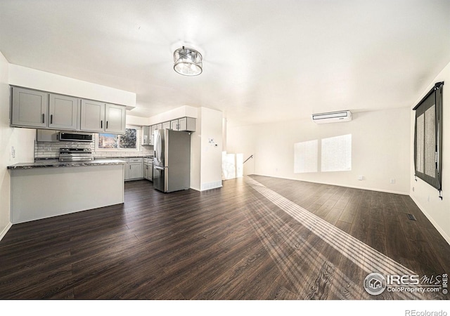 kitchen with dark wood-type flooring, appliances with stainless steel finishes, gray cabinets, and decorative backsplash