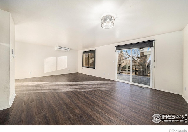 spare room with a wall unit AC and dark wood-type flooring