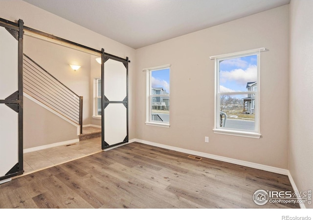 unfurnished room with hardwood / wood-style floors and a barn door