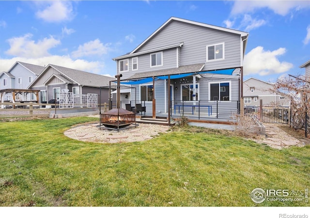 rear view of house with a fire pit, a lawn, and a wooden deck