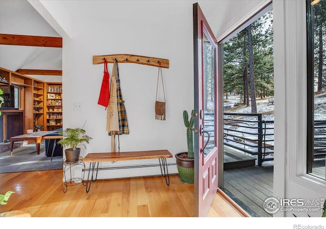 interior space with a baseboard heating unit, beamed ceiling, and wood finished floors