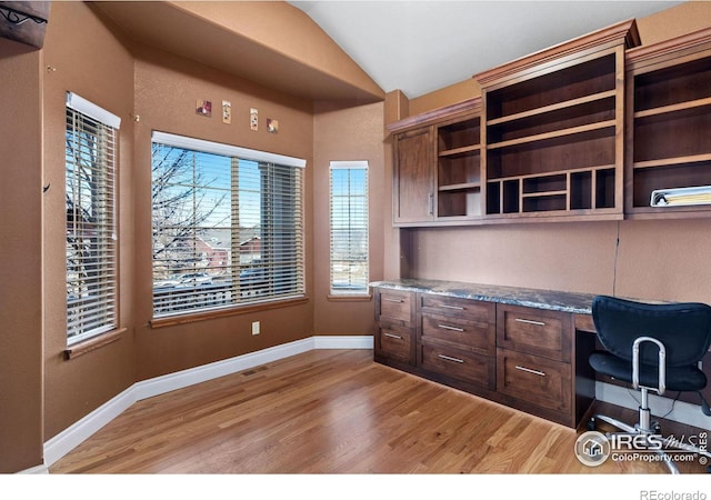 office with light wood-type flooring, built in desk, and vaulted ceiling