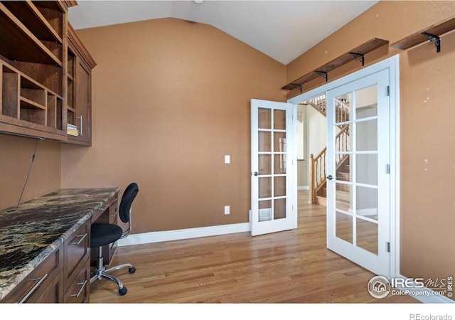 office featuring light hardwood / wood-style flooring, built in desk, vaulted ceiling, and french doors