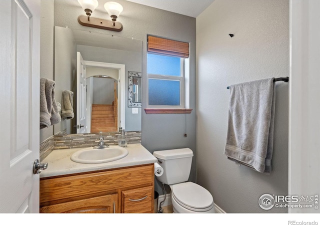 bathroom with vanity, decorative backsplash, and toilet