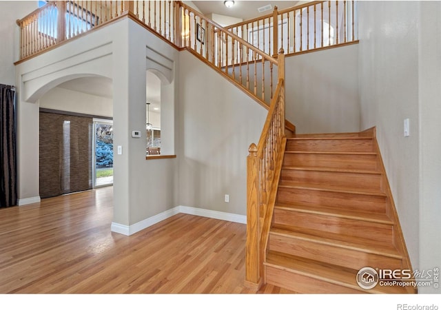 staircase featuring a towering ceiling and wood-type flooring