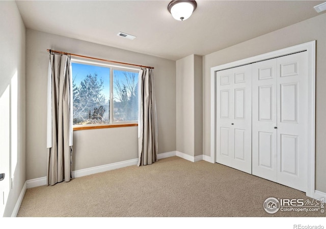 unfurnished bedroom featuring light carpet and a closet