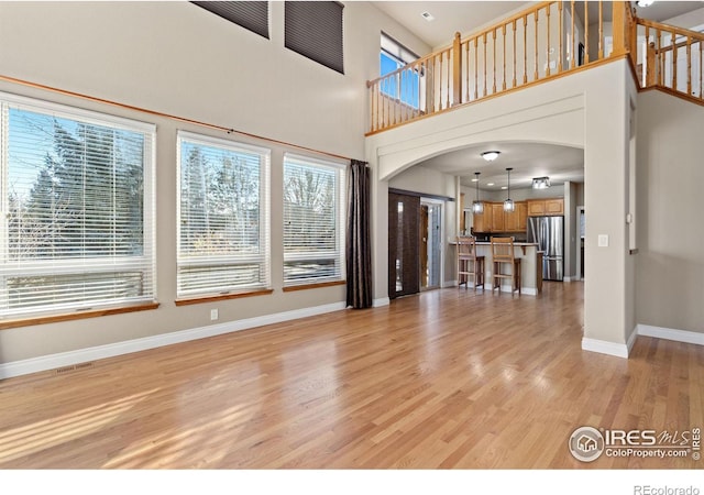 unfurnished living room featuring a towering ceiling and light wood-type flooring