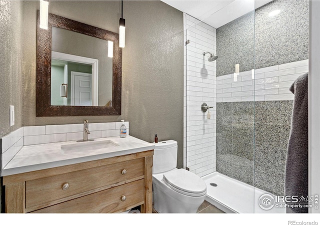 bathroom featuring vanity, tiled shower, and toilet