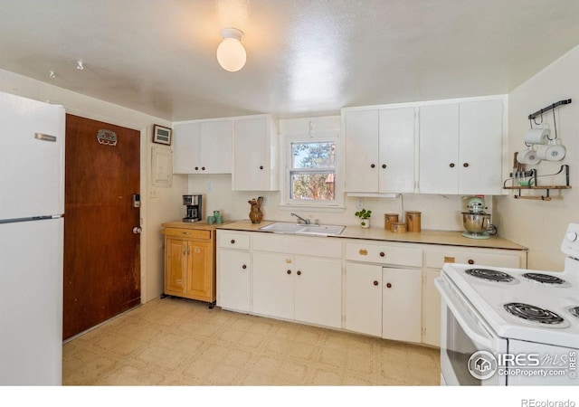 kitchen featuring white appliances, white cabinetry, and sink