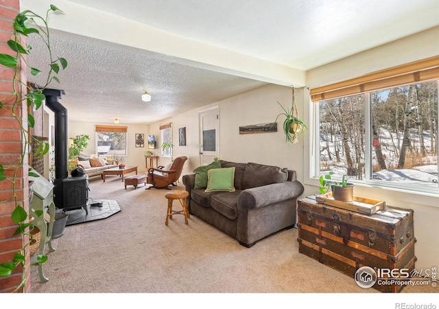 carpeted living room with beam ceiling, a wood stove, and a textured ceiling