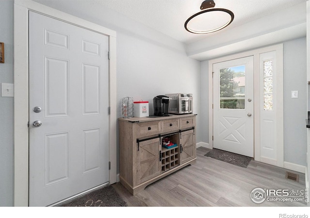 entryway with a textured ceiling and light hardwood / wood-style floors