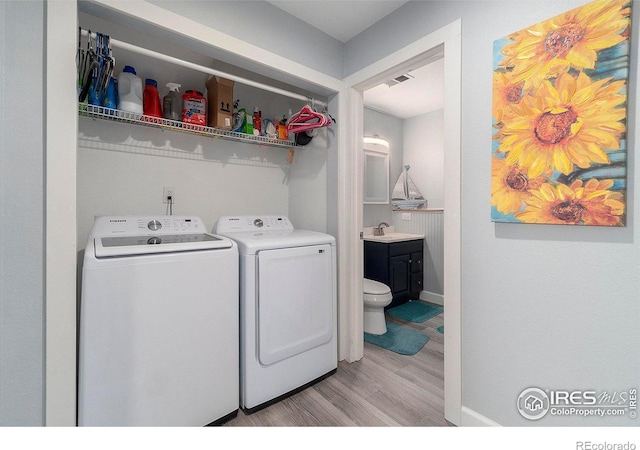 laundry area featuring light hardwood / wood-style floors, washing machine and dryer, and sink