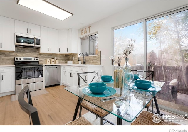 kitchen with white cabinetry, sink, tasteful backsplash, light hardwood / wood-style flooring, and appliances with stainless steel finishes