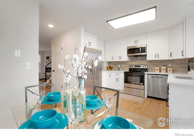 kitchen featuring tasteful backsplash, appliances with stainless steel finishes, light countertops, white cabinetry, and a sink