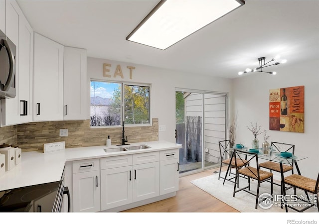 kitchen featuring light countertops, a sink, backsplash, and white cabinetry