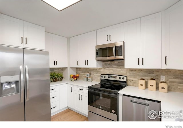 kitchen with stainless steel appliances, white cabinets, light countertops, light wood-type flooring, and decorative backsplash