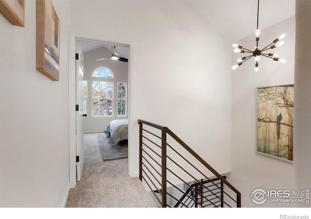 hall with an upstairs landing, high vaulted ceiling, a notable chandelier, and light colored carpet