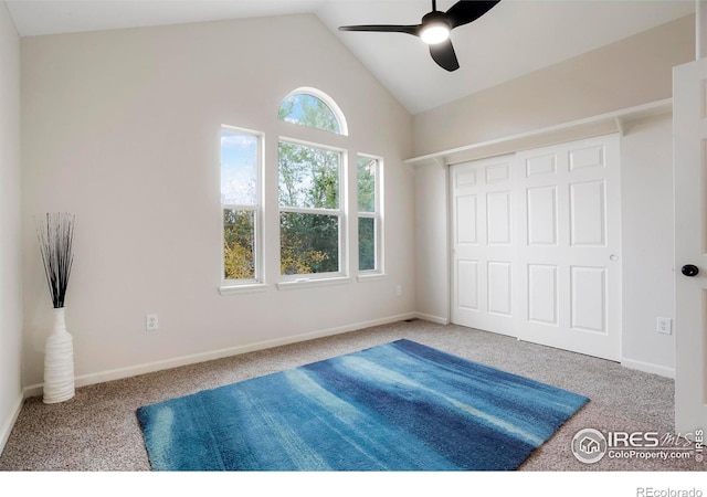 carpeted bedroom with lofted ceiling, a closet, baseboards, and a ceiling fan