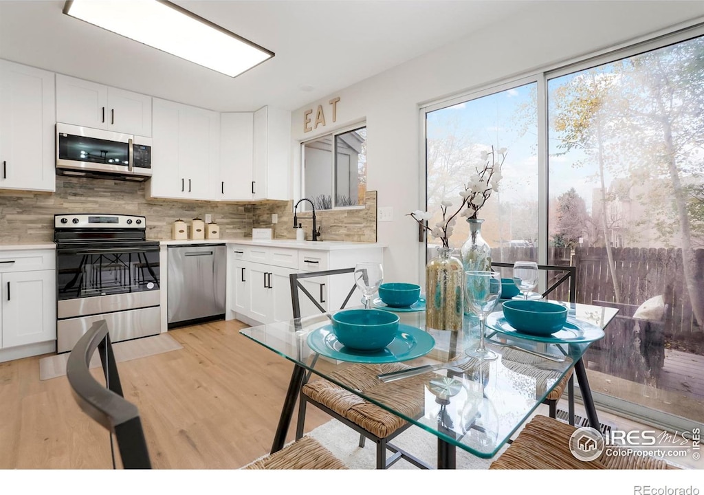 kitchen with stainless steel appliances, light countertops, white cabinetry, and decorative backsplash