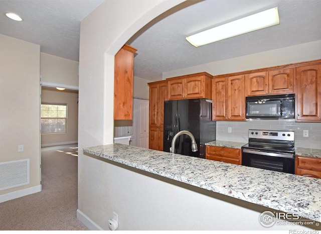 kitchen with black appliances, sink, tasteful backsplash, light stone counters, and carpet floors